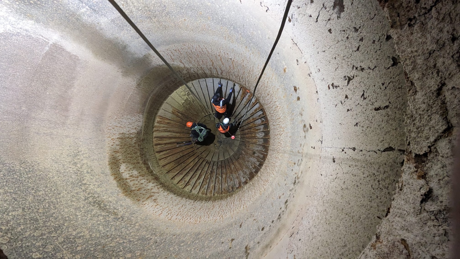 Blick von oben in ein Silo mit zwei Technikern auf der Arbeitsbühne